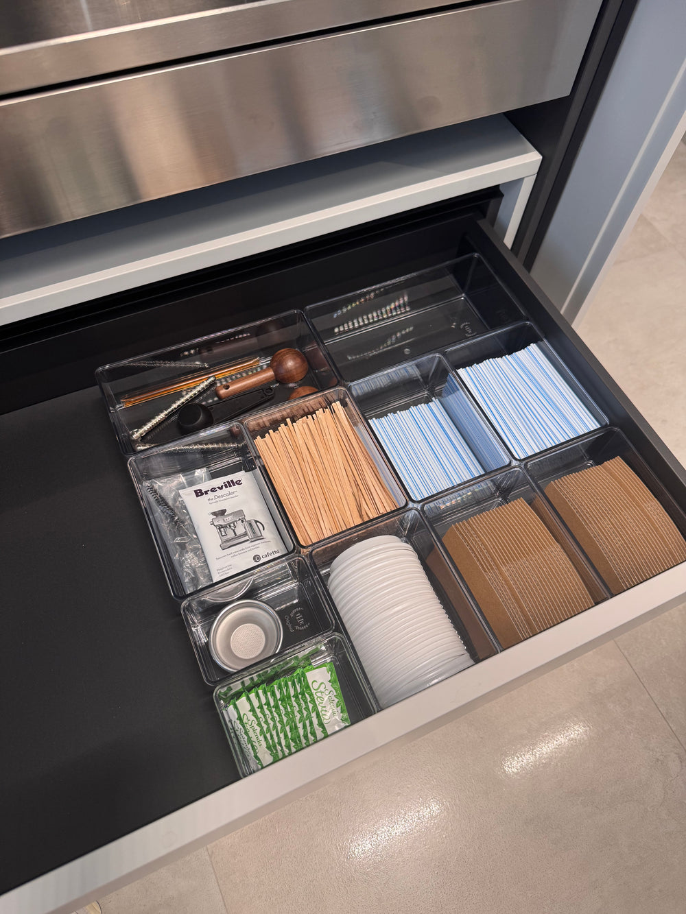 Gaveta de accesorios de café organizada con divisores transparentes