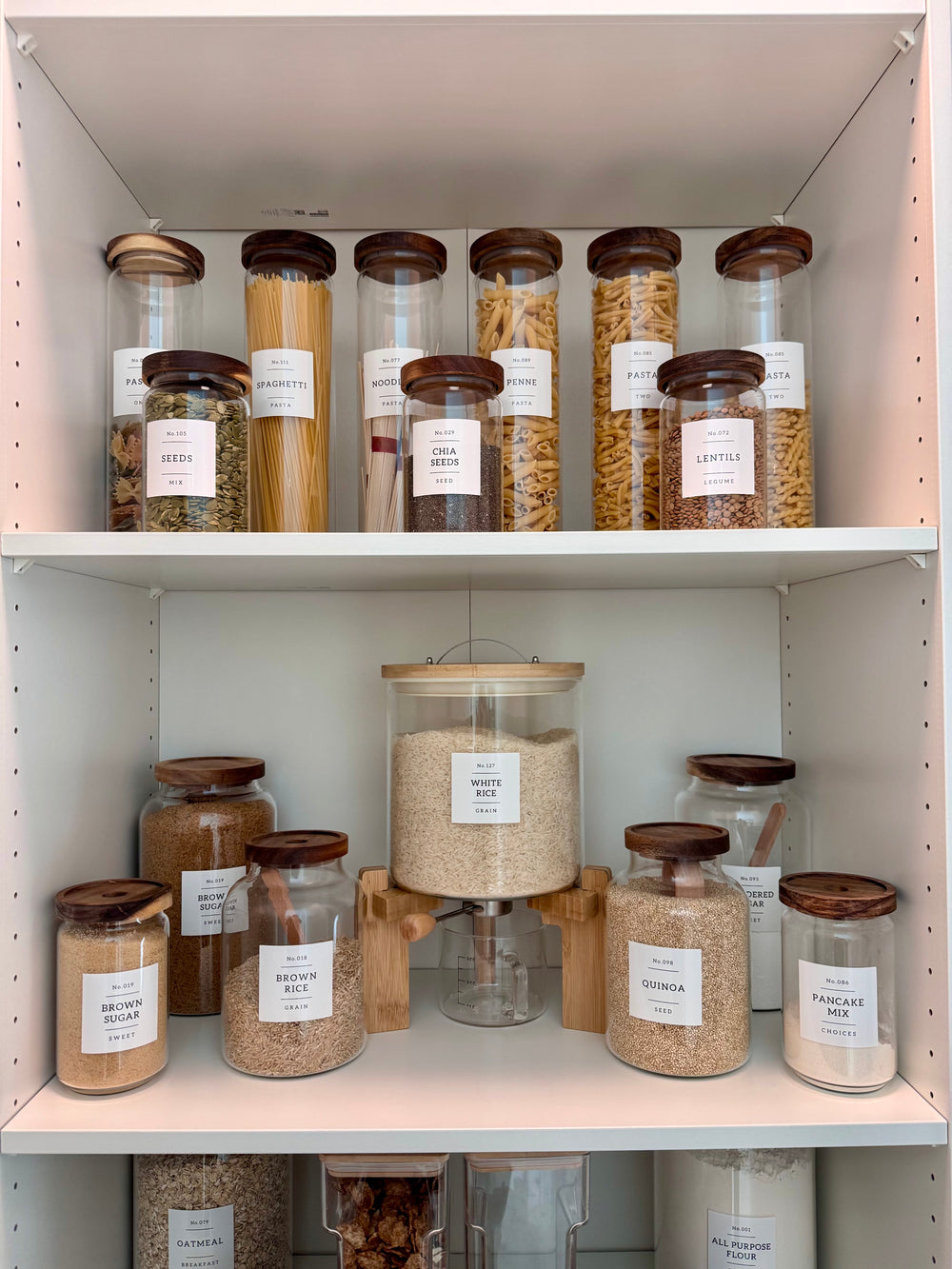 Frascos de pasta, arroz y granos con etiquetas en una despensa organizada